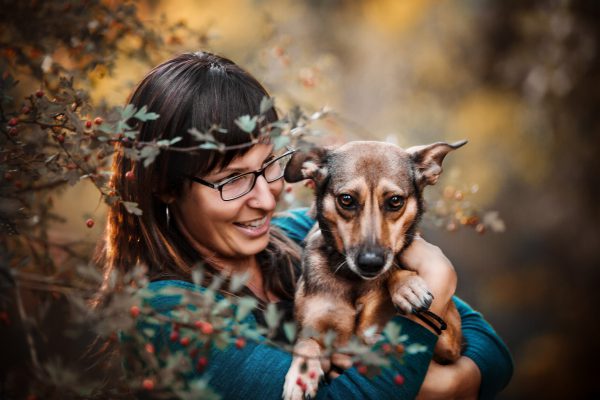 Beeld van een vrouw met hond in de camera, herfstsetting